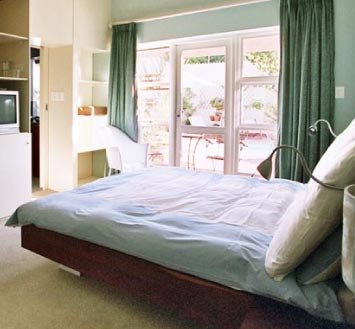 Standard Room at Rosedene Lodge with a double bed, built-in shelves and glass doors to the courtyard